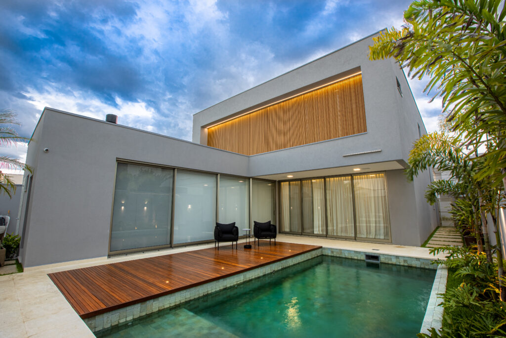 Fachada contemporânea com piscina e brise de madeira — projeto residencial assinado por João Gobbo em São José dos Campos.
