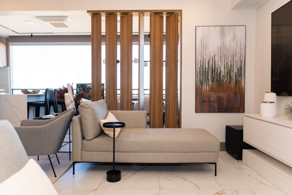 Sala de estar com chaise bege e painel ripado em madeira — projeto de interiores moderno e acolhedor por João Gobbo.