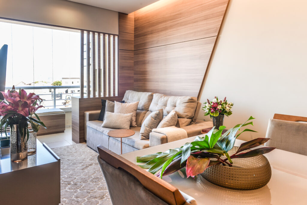 Sala de estar integrada com painel de madeira, sofá em tons neutros e decoração afetiva — projeto de interiores por João Gobbo.
